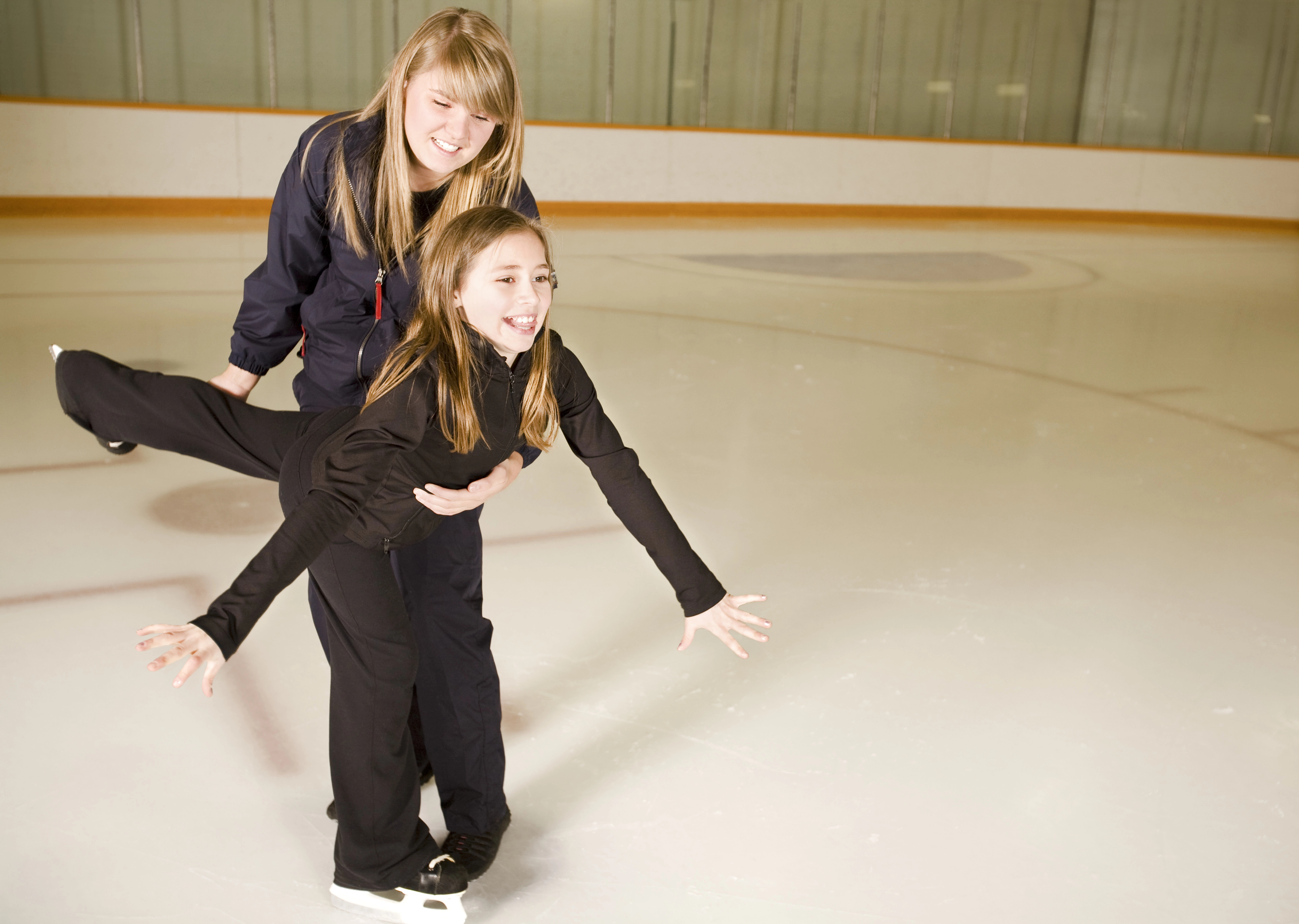 Beginner skater smiling and laughing while learning with a certified instructor on the ice